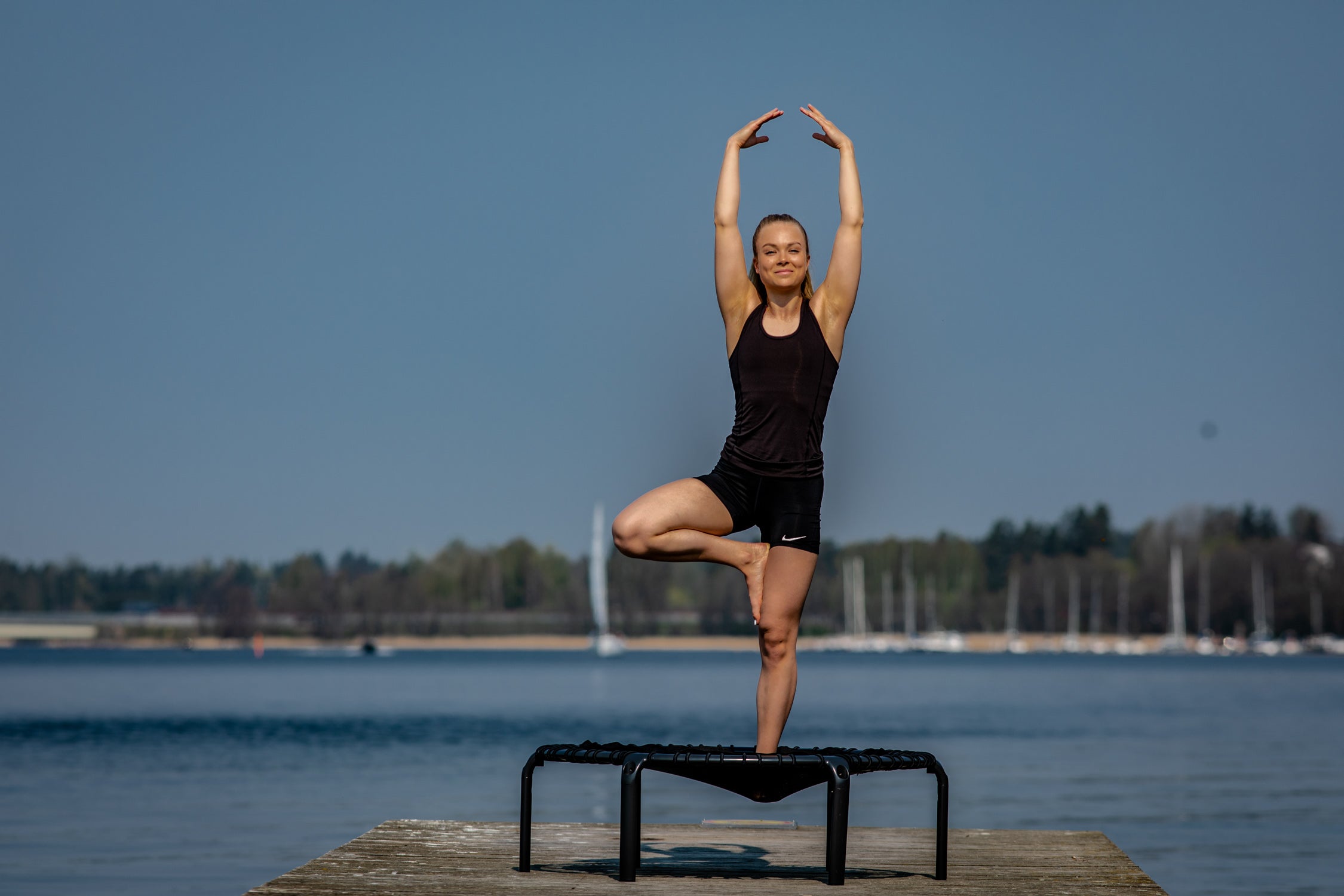 A woman practicing trampoline yoga on an ACON rebounder