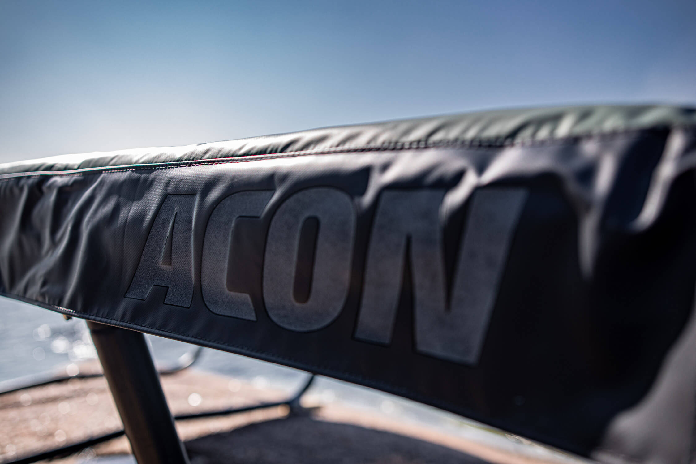 A closeup of green trampoline springs padding with white ACON logo printed