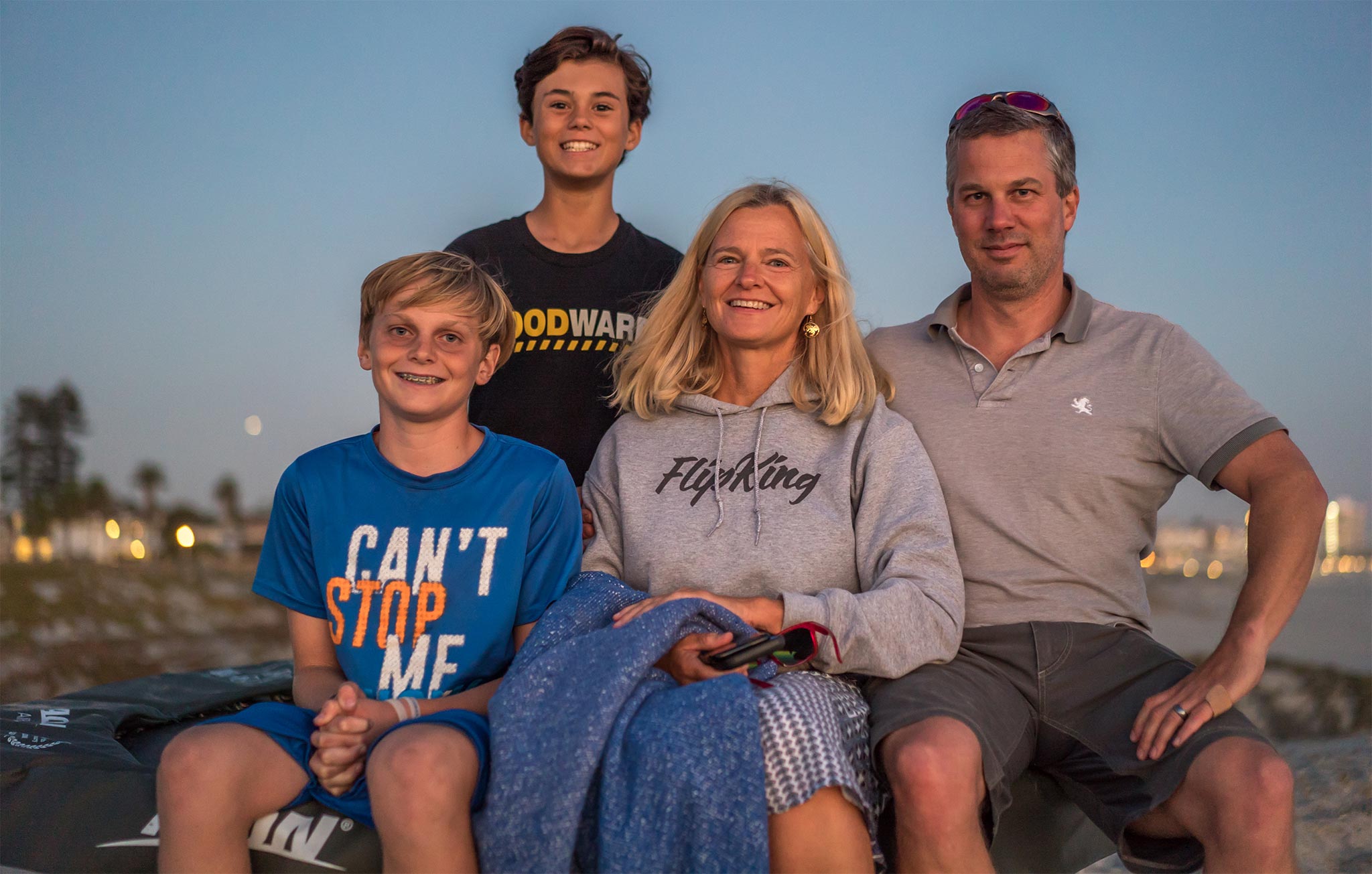 Acon customer family with a mom and three boys sitting on the beach