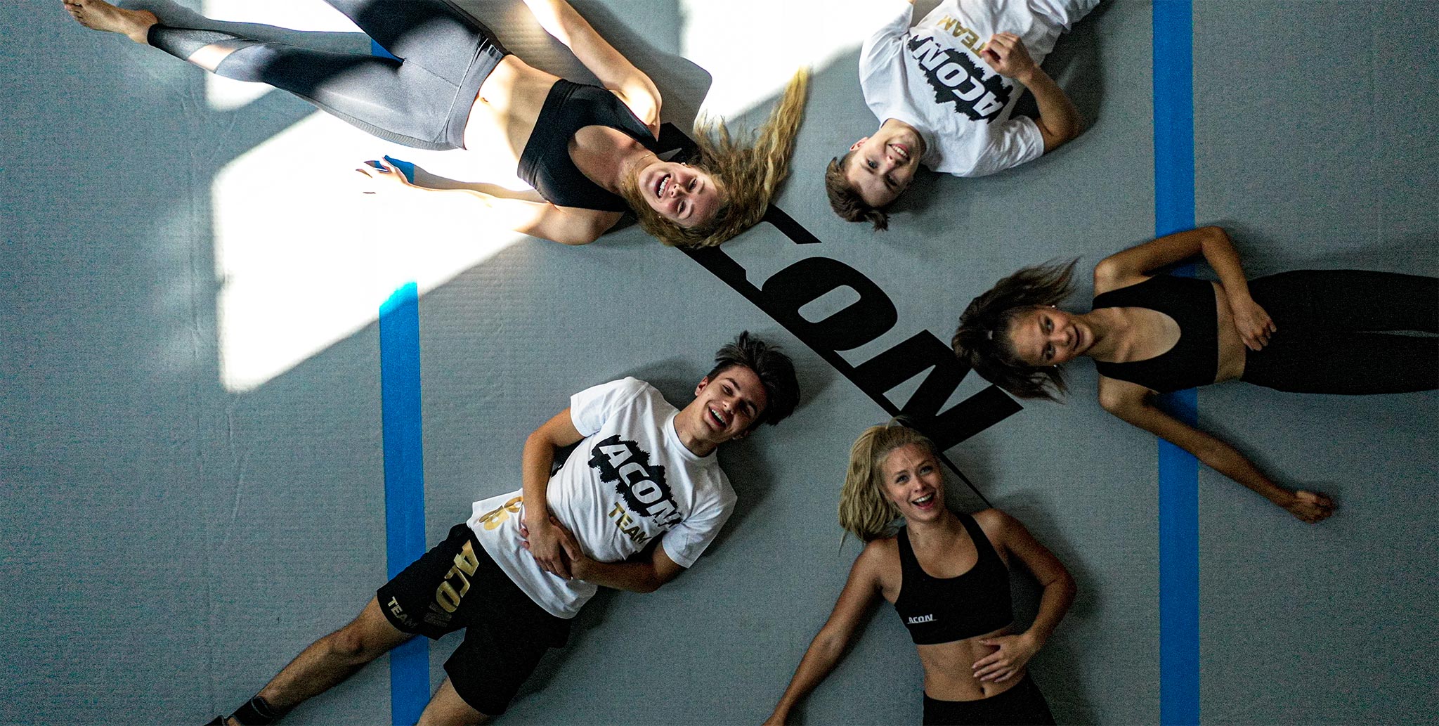 Five people belonging to Acon team lying on a big Airtrack. Picture is taken from the bird’s eye view 