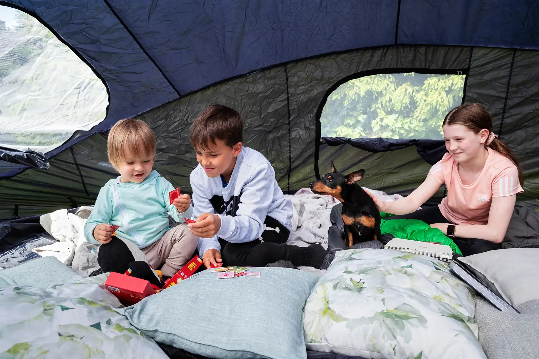 Three kids and a dog hanging inside of an Acon trampoline tent.