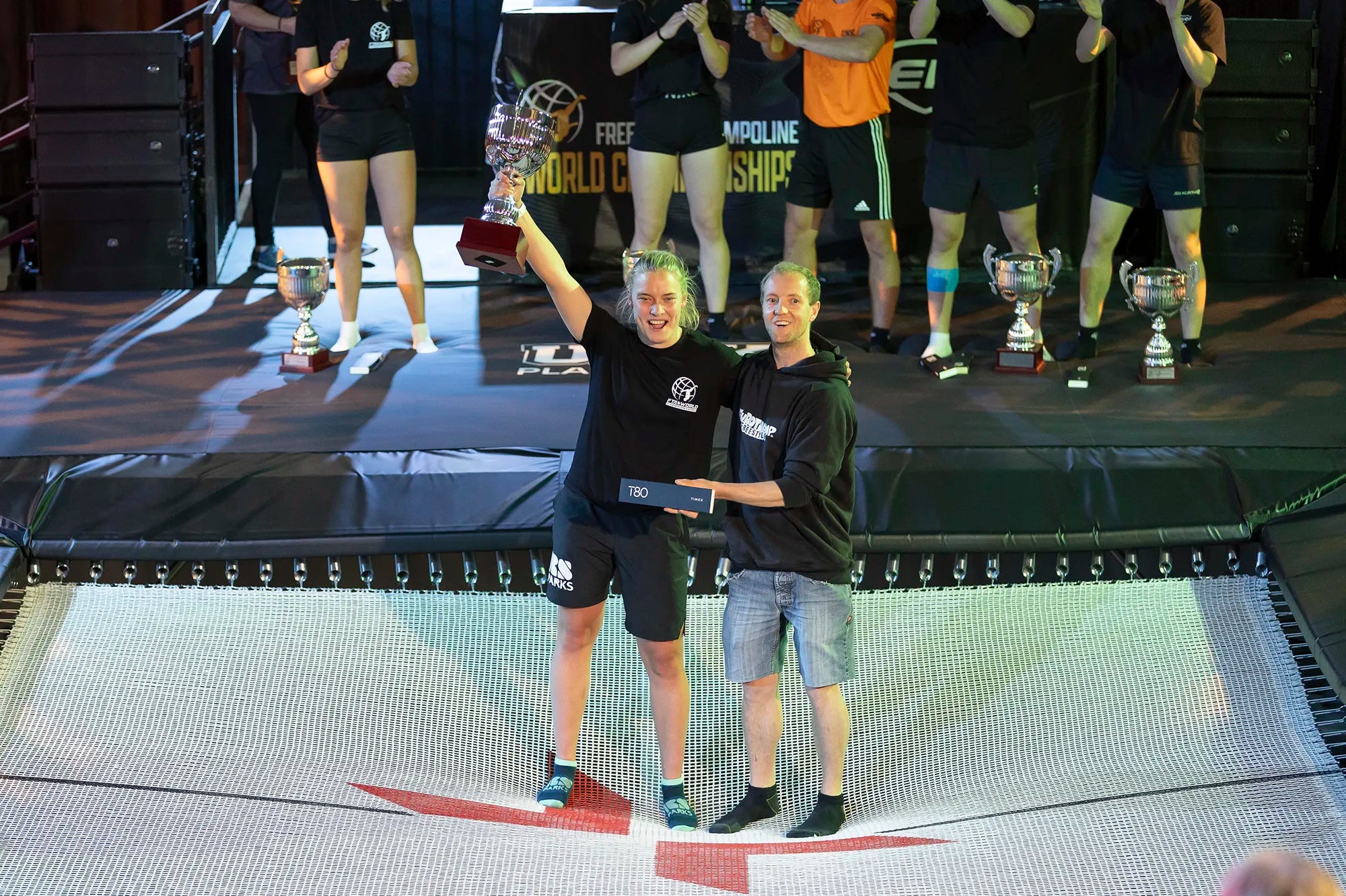 The winner of the trampoline competition holding a trophy on a trampoline.