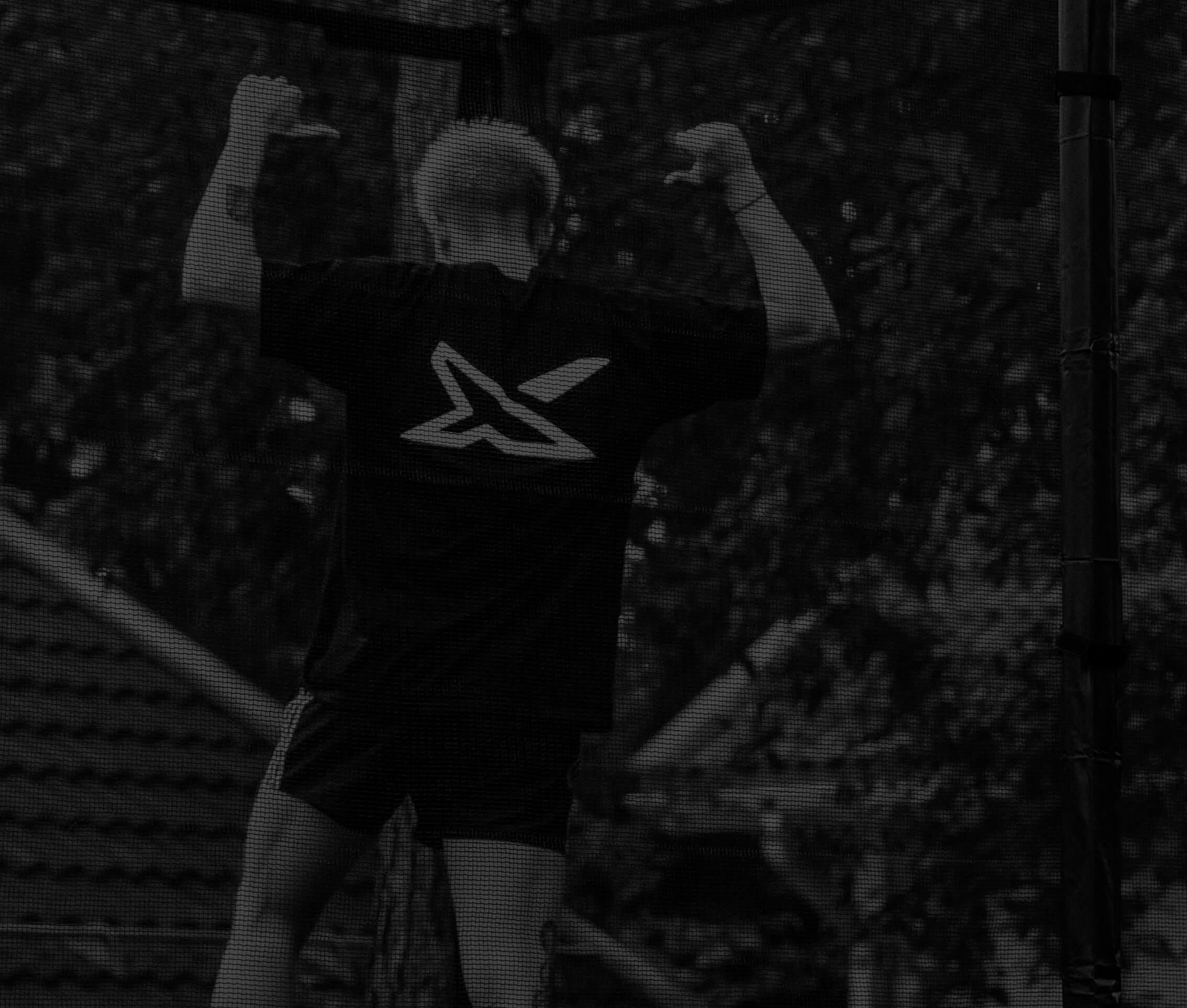 Aleksi Sainio, seen from behind, standing on the ACON X Trampoline and pointing to his X t-shirt.