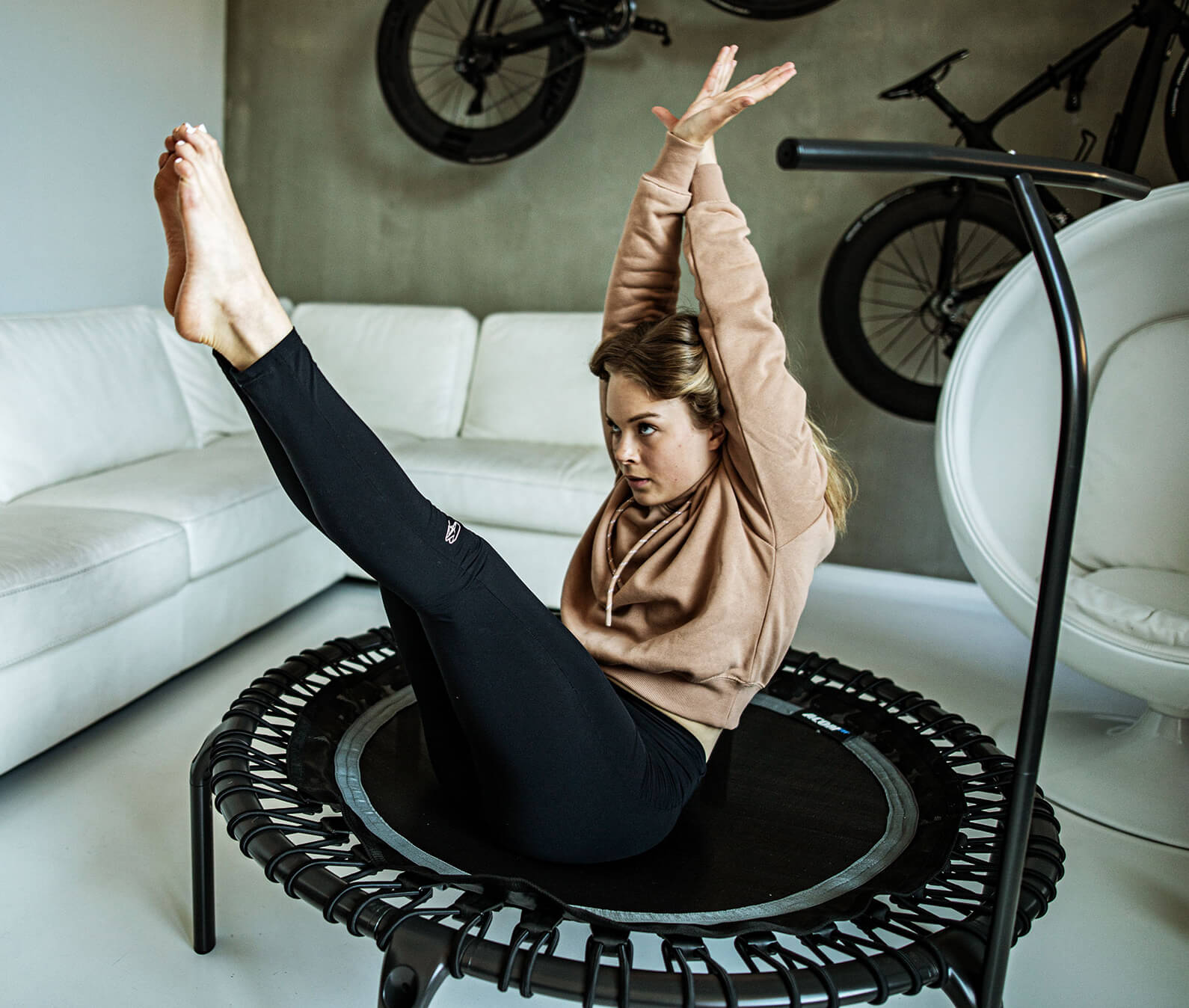 Woman doing a core exercise on a fitness rebounder in her livingroom.