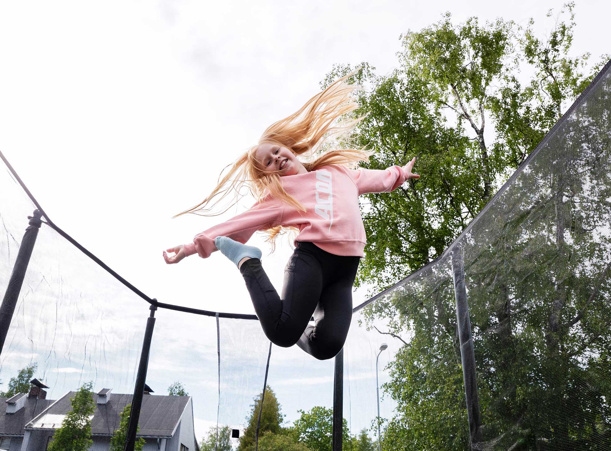 A girl wearing pink Acon college shirt jumps on trampoline