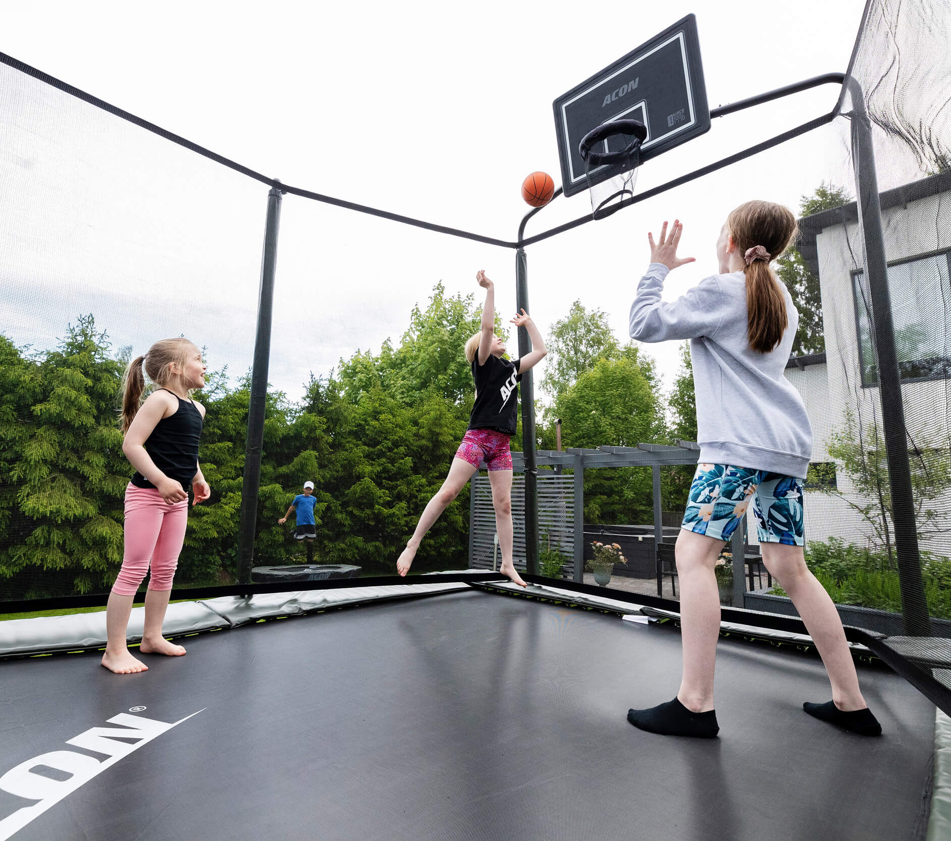 3 girls playing basketball on a trampoline.