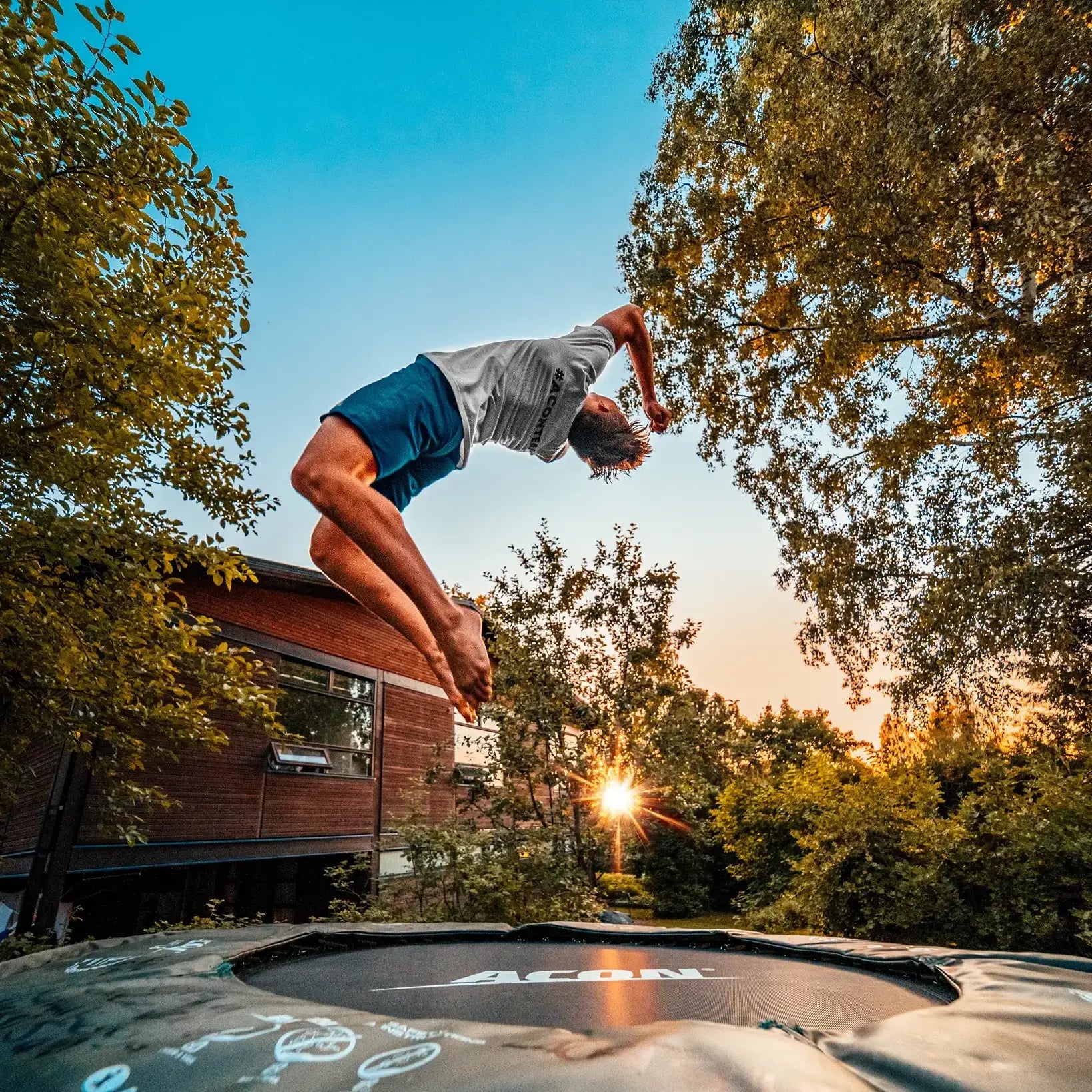 Boy doing a flip with a smaller round Acon trampoline. 