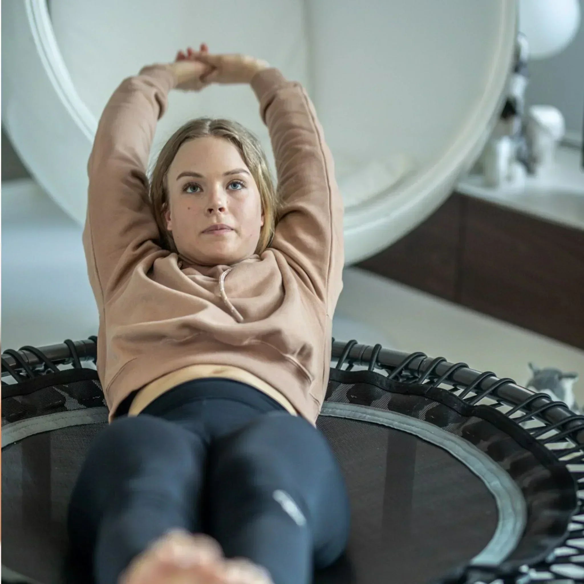 woman laying on a acon minitrampoline and working out her abs. 
