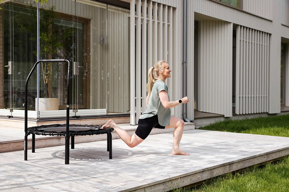 Woman doing a single leg squat on an Acon rebounder. 