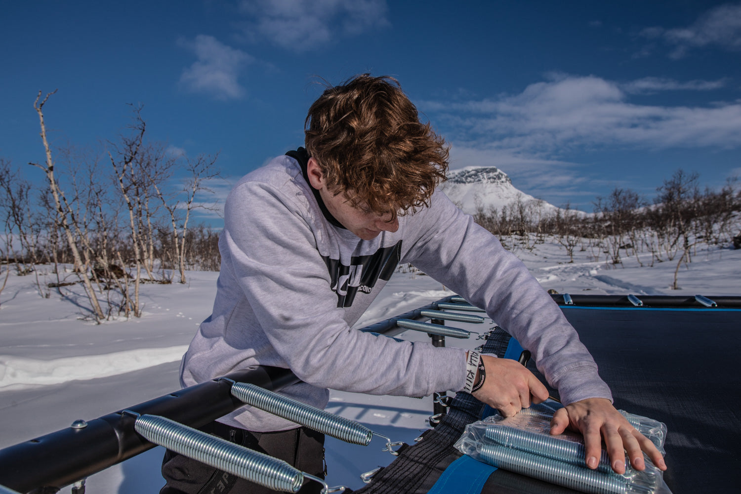 Young guy fixing and replacing trampoline springs
