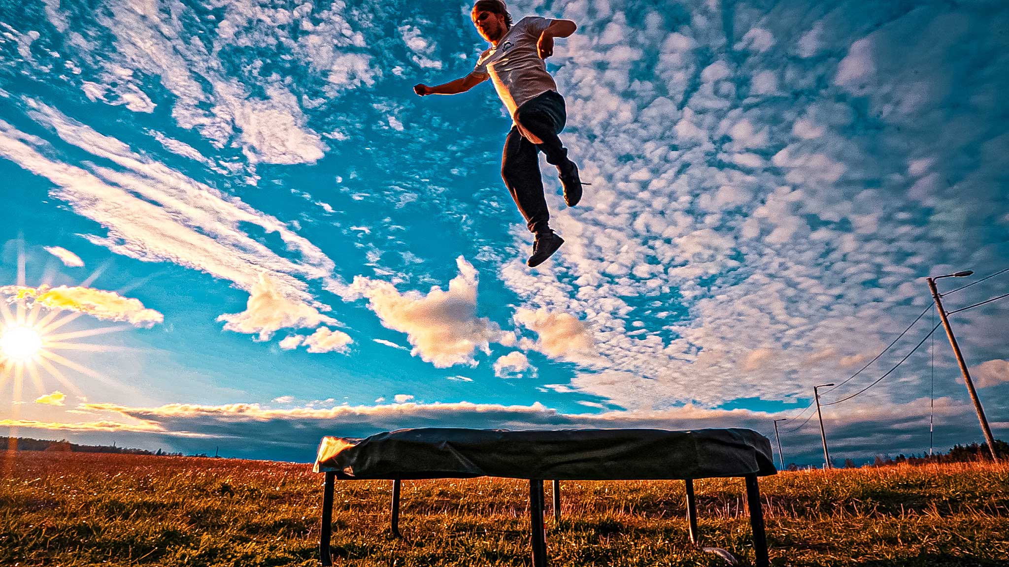 A man jumping on an Acon trampoline while sun is rising in the background.