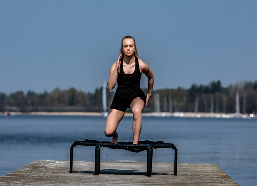 A woman taking running steps on fitness trampoline in marina