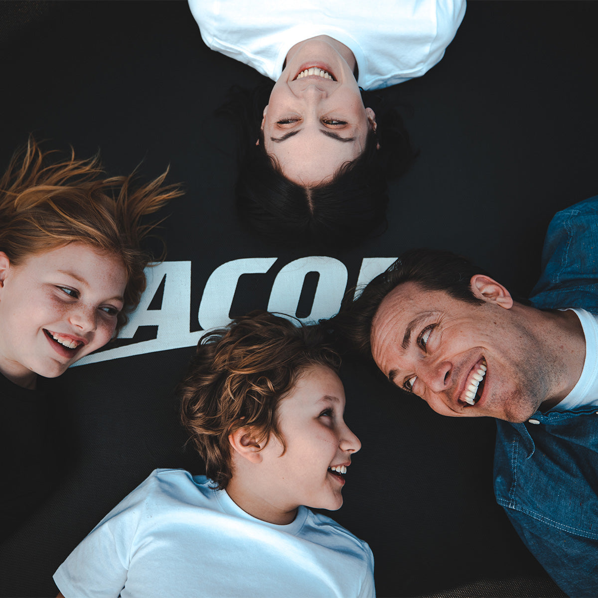 A family of four laying on an ACON trampoline