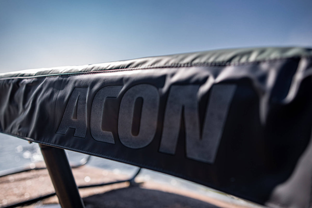 A closeup of green trampoline springs padding with white ACON logo printed
