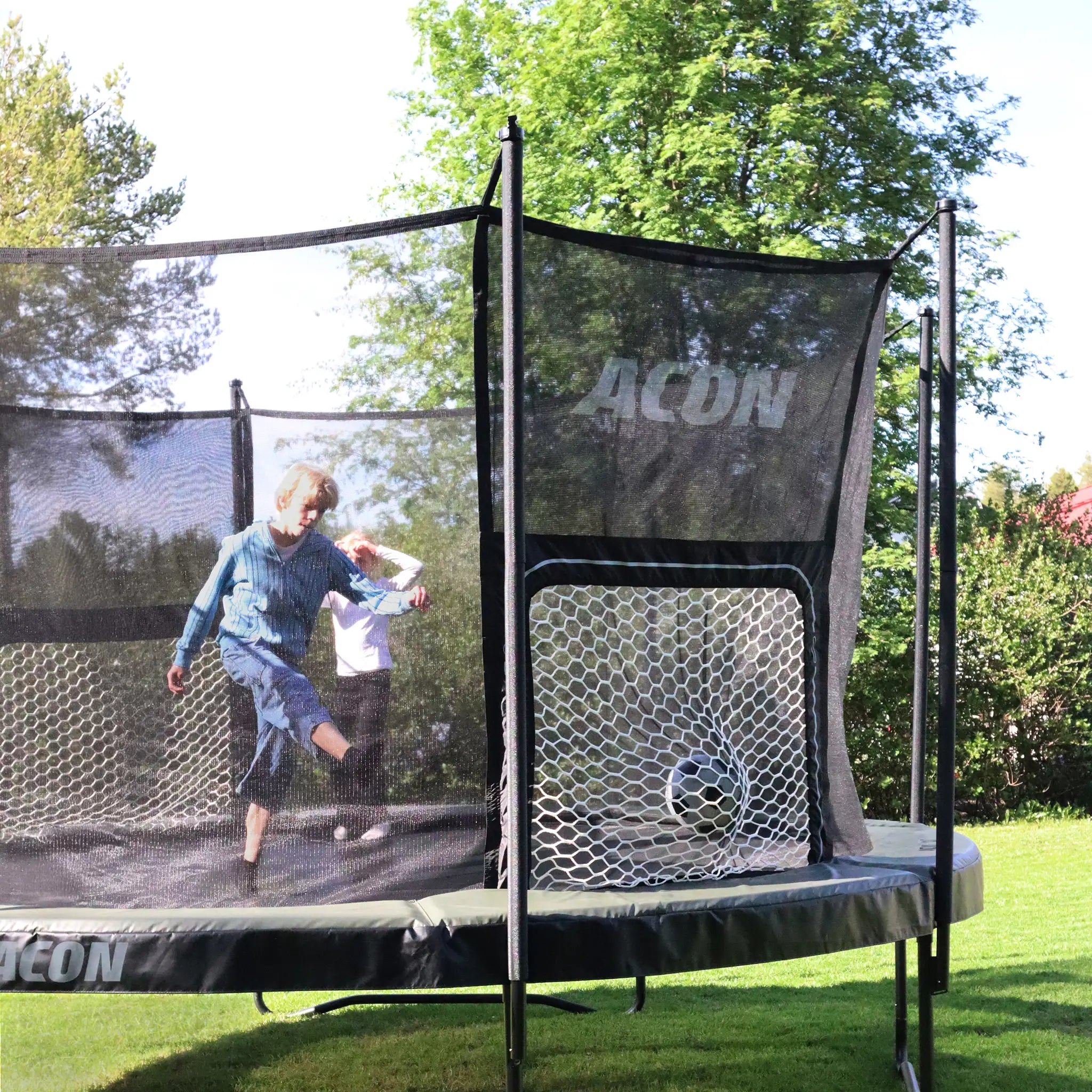 Children playing soccer on an ACON Air Round trampoline on grass.