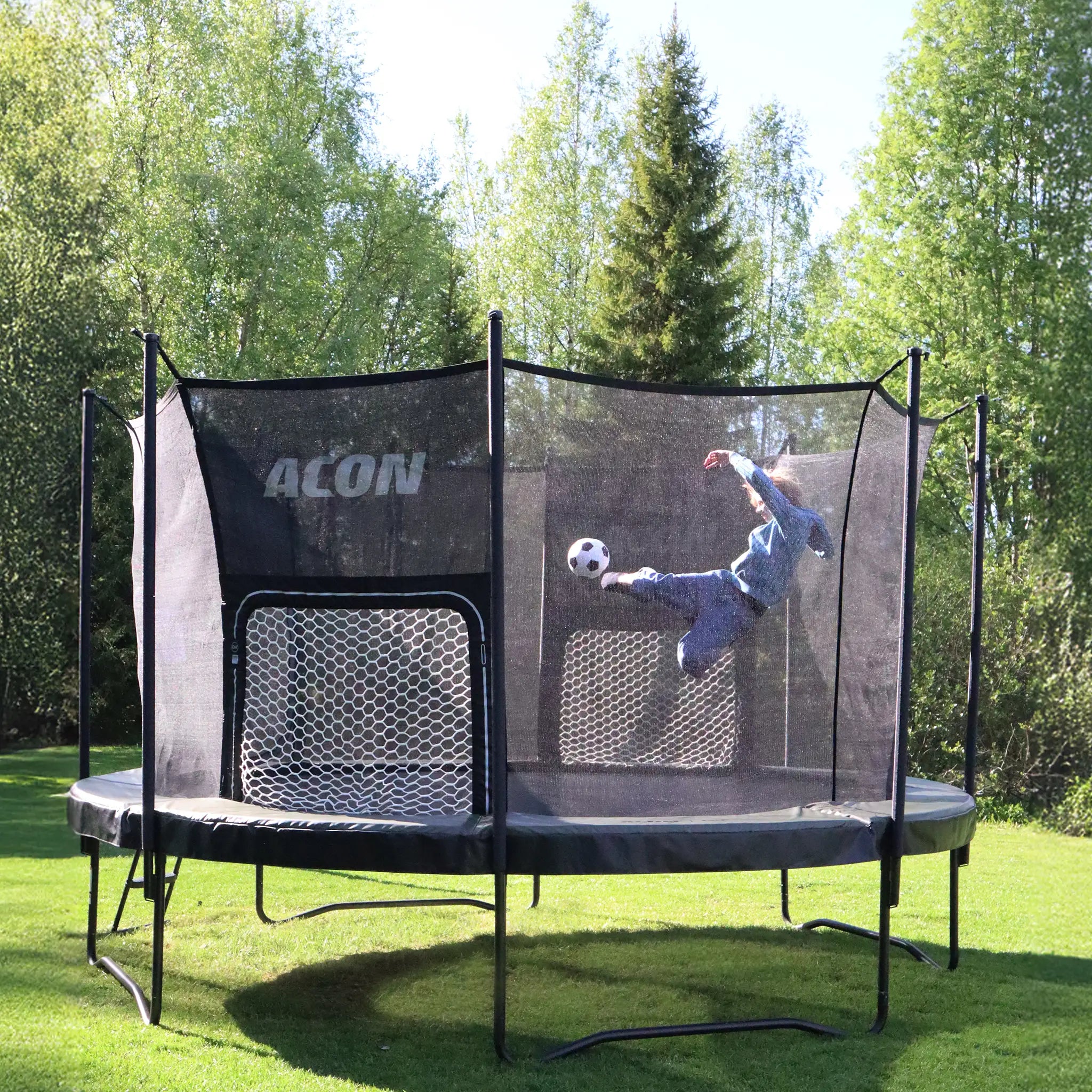 Child kicking a ball toward the ACON Air Soccer Goal inside a trampoline.