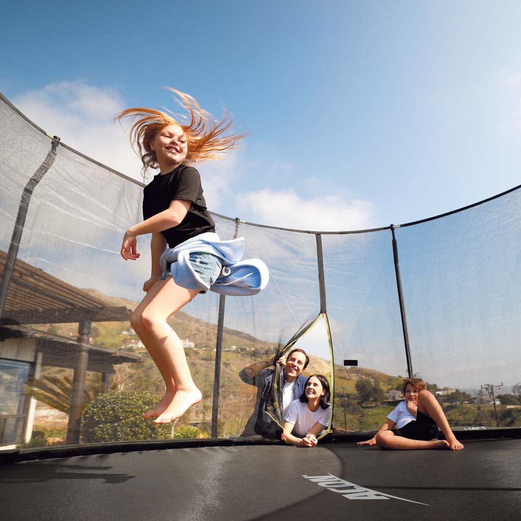A girl jumping on an Acon trampoline, family watching
