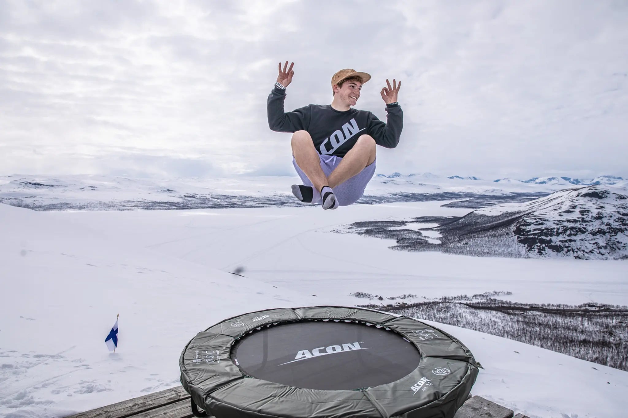 Person jumping on an Acon trampoline in a snowy mountain landscape.