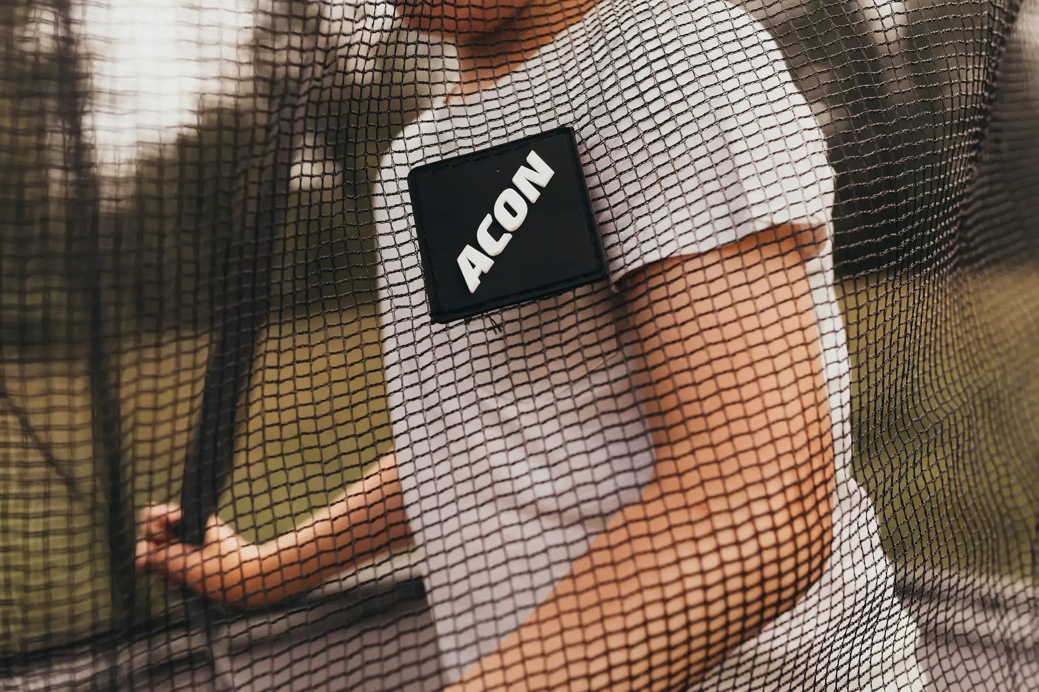 Close-up of a person standing inside an Acon trampoline, seen through the safety net.