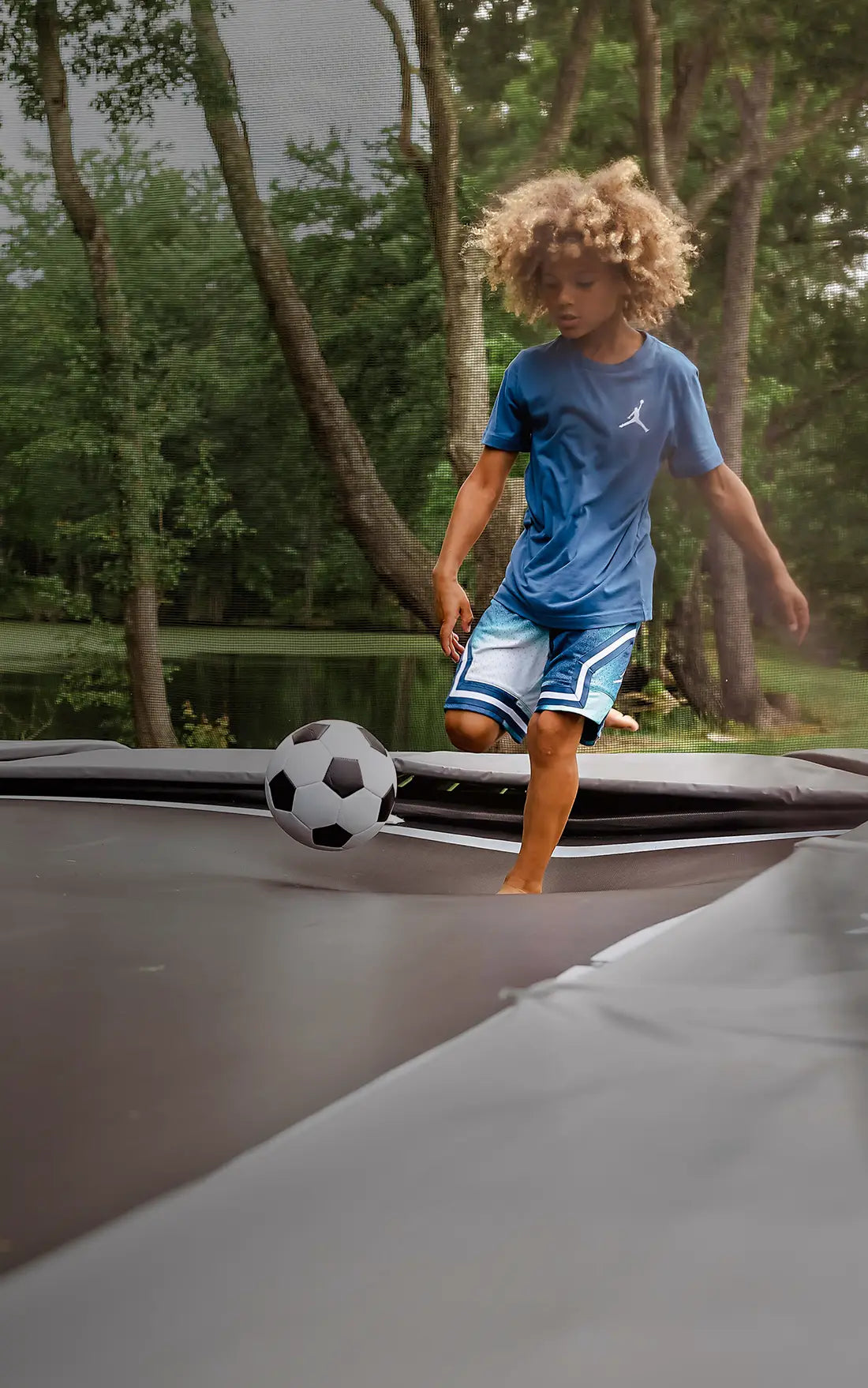 A boy plays football on the Acon X Trampoline.