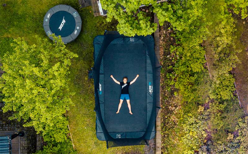 Round and rectangular trampoline in a garden, seen above