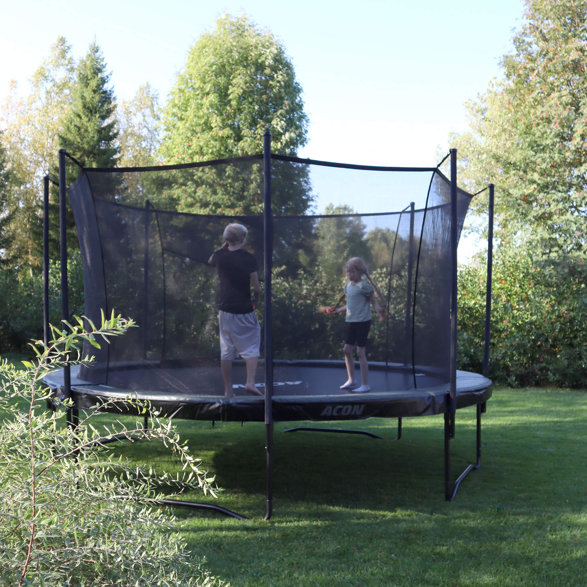 Acon Air trampoline in a summer backyard. Two children jumping on the trampoline.