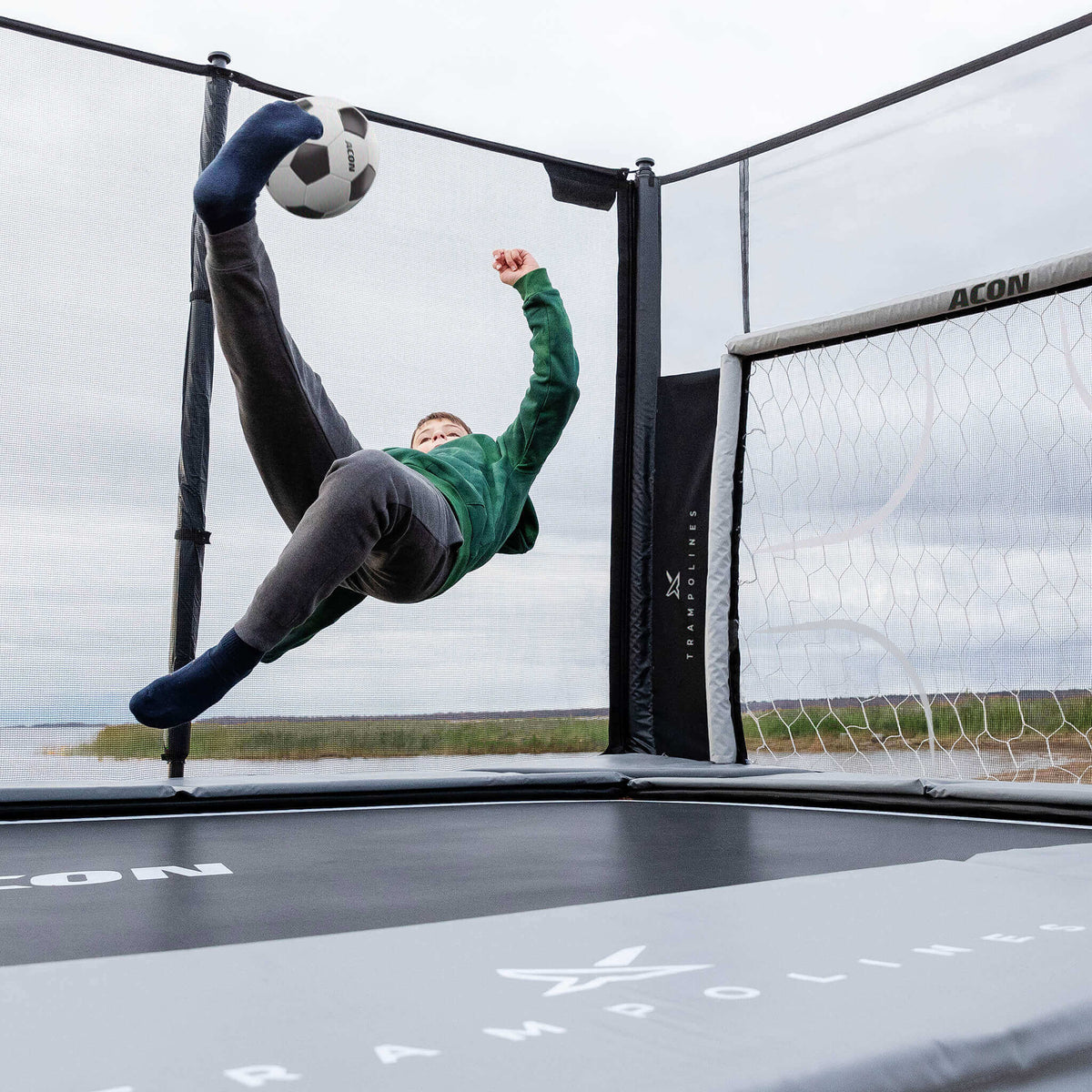 Two boys playing soccer on Acon X 17ft Trampoline with soccer panel
