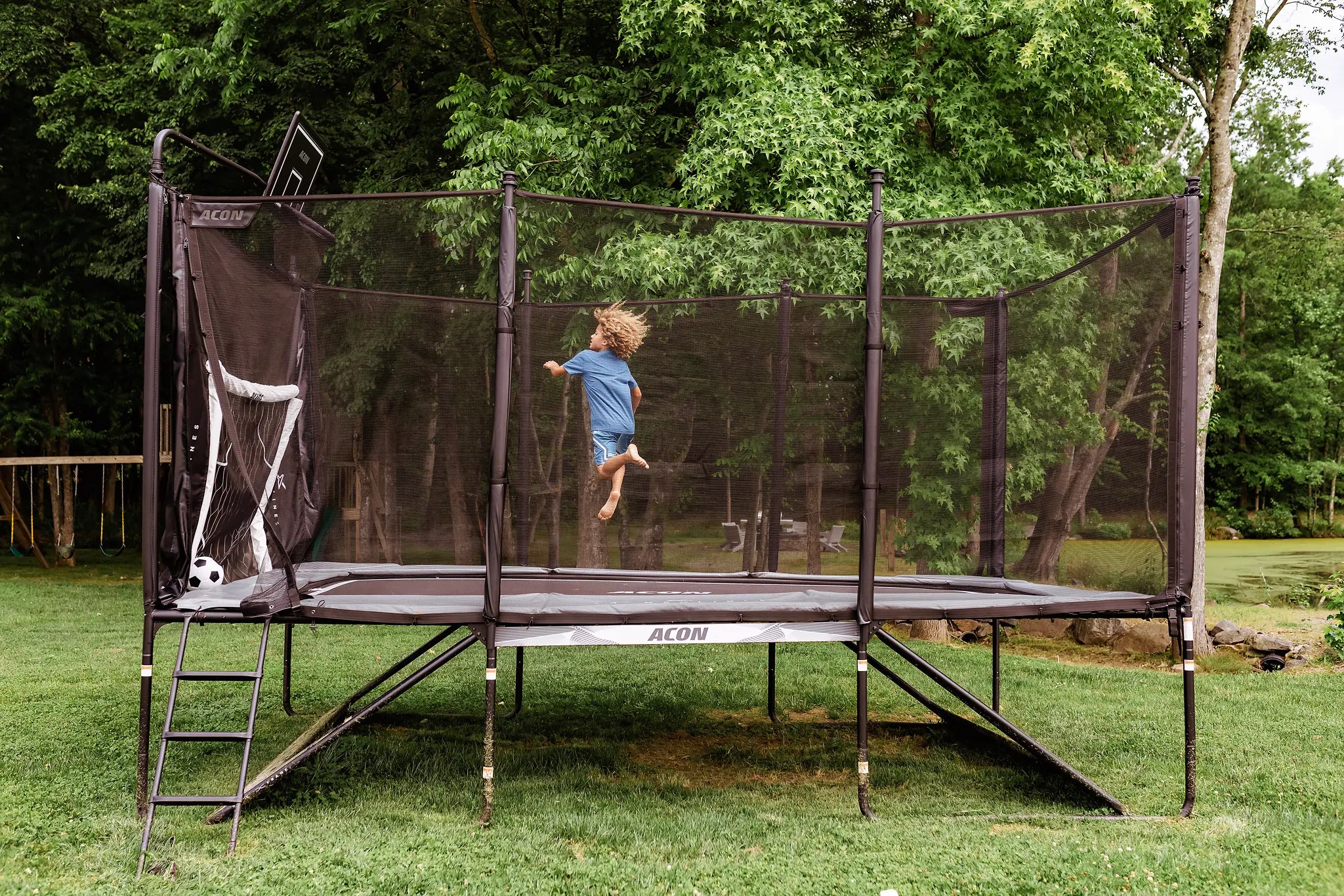Boy playing on a Acon X trampoline with basketball hoop. 
