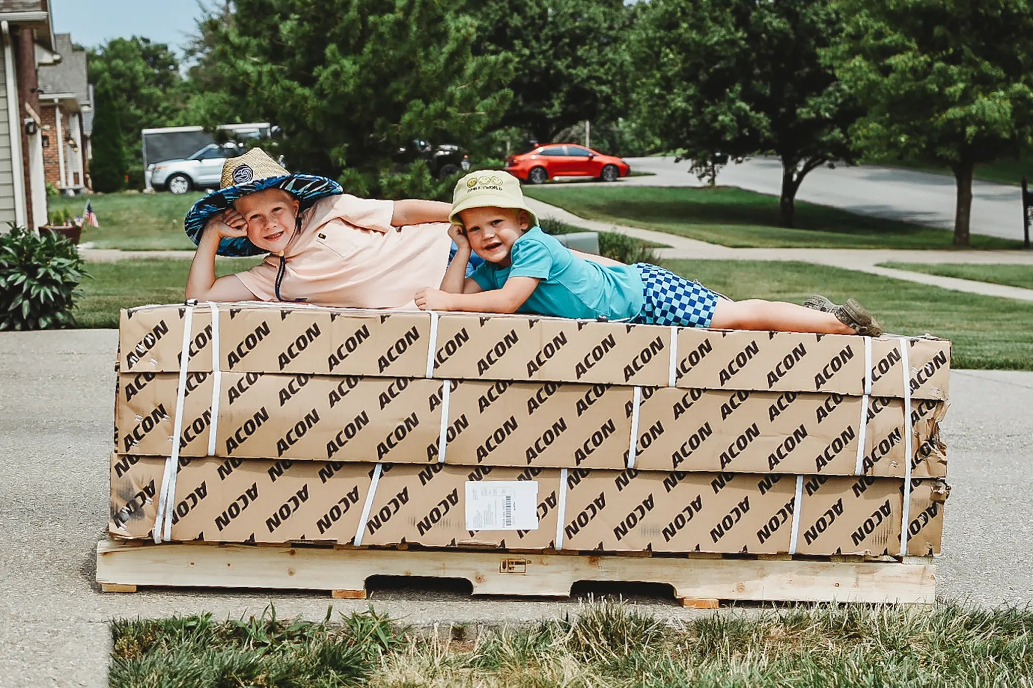 Two boys laying on top of Acon trampoline packages. 