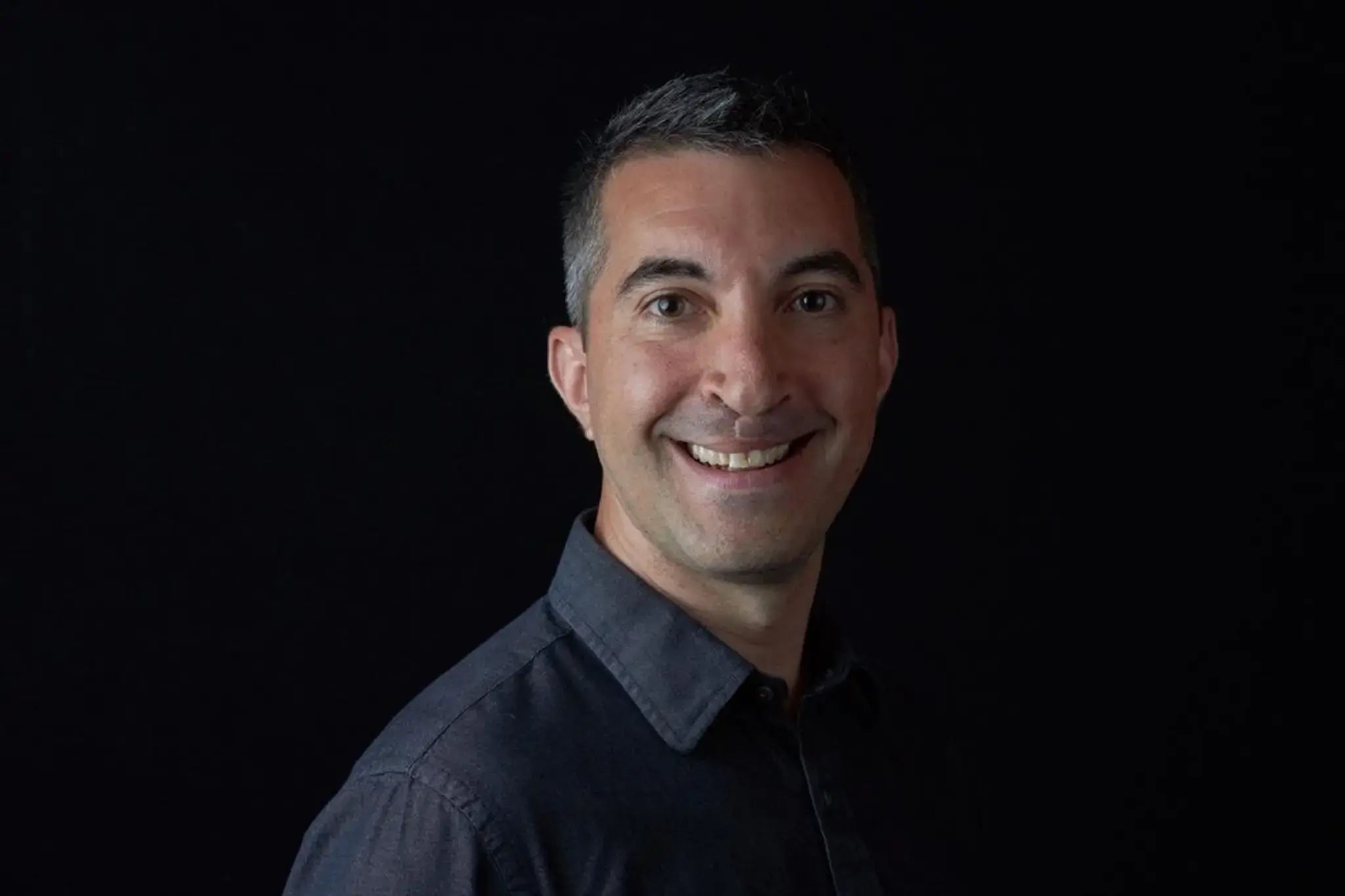 Head-and-shoulders portrait of Acon's Product Specialist Dave Hepp smiling, with  a black background.