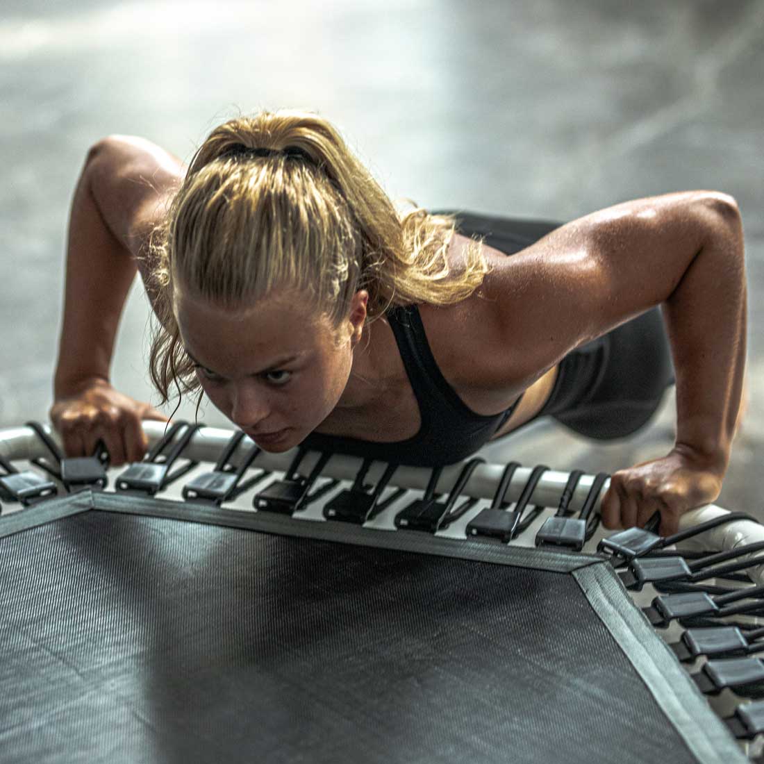 Woman exercising on the Acon FIT 55in white Hexagon trampoline.