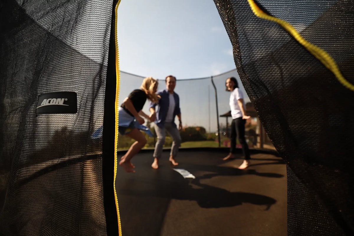 Family playing together on an Acon trampoline with safety enclosure.