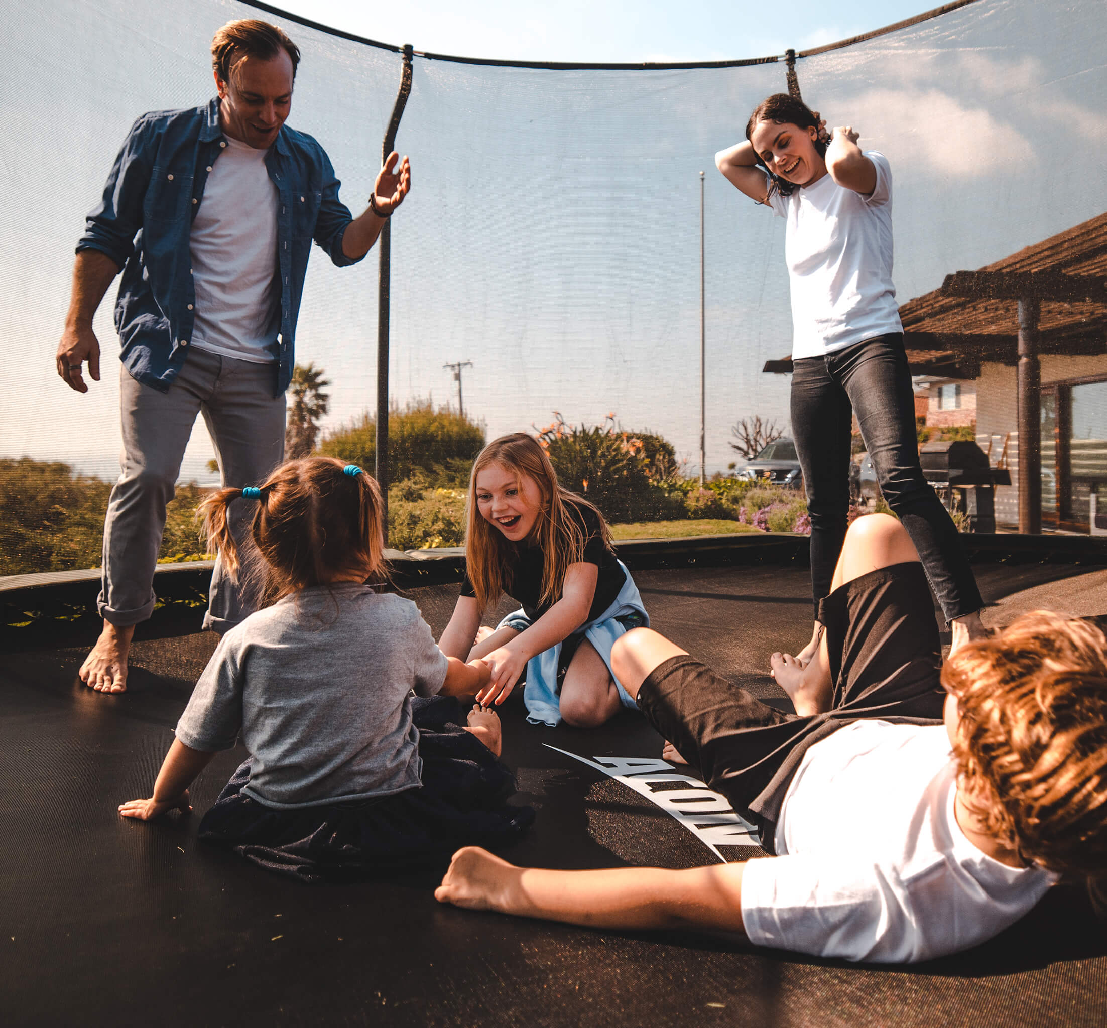 Mom, dad and three kids playing on an Acon trampoline.