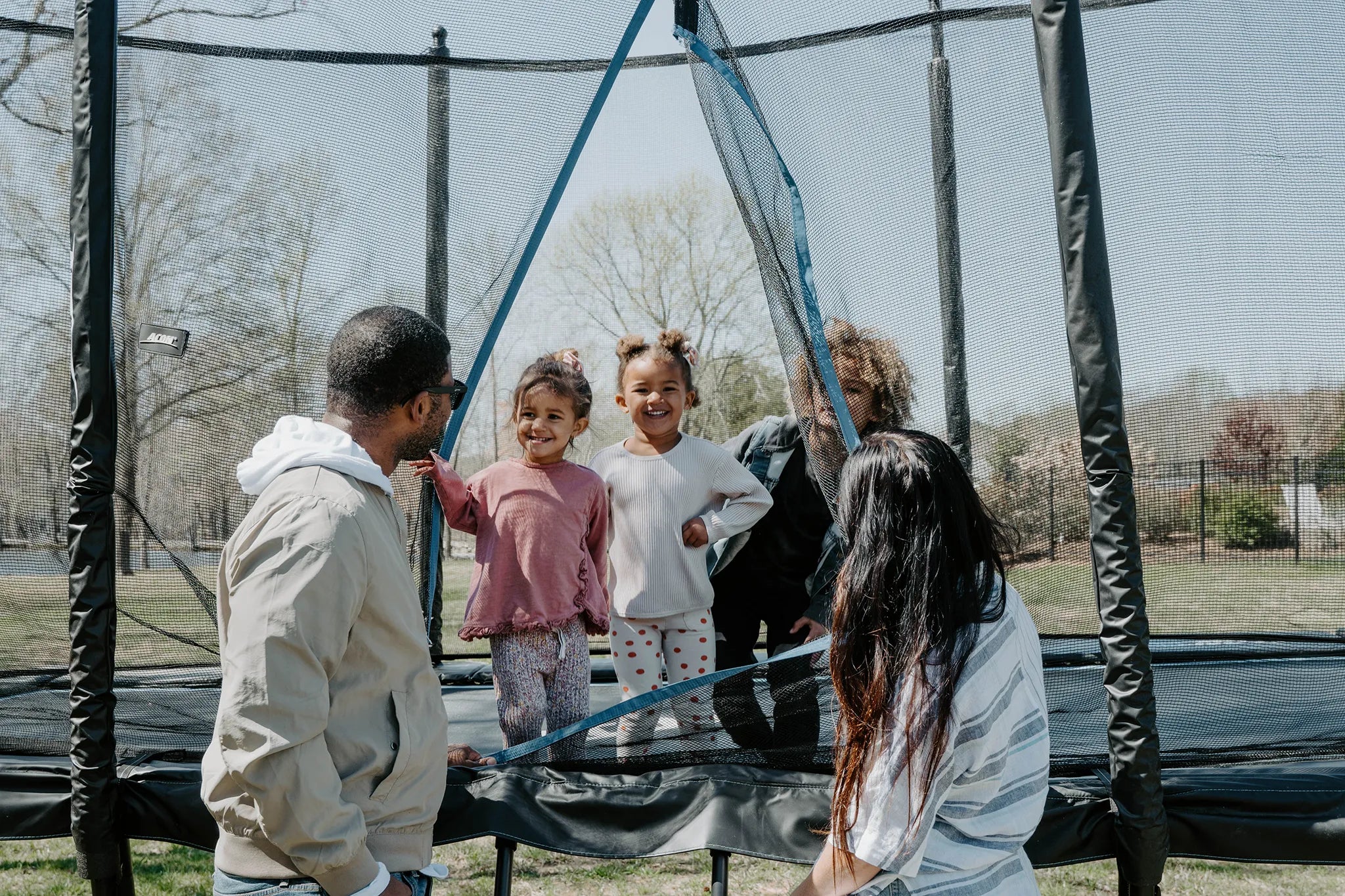 Family with kids enjoying Acon trampoline safely with enclosure net.