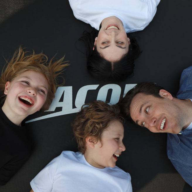Happy faces of a family lying on the Acon trampoline