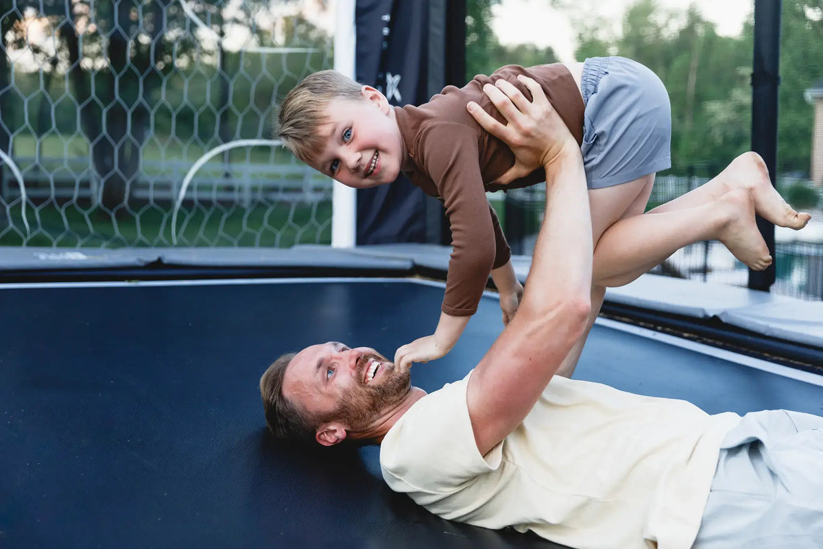 Father and child playing together on an ACON trampoline.
