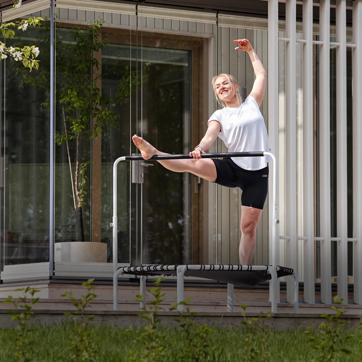 Fit 44in Round Rebounder with Balance Handlebar used for outdoor stretching routine on the terrace.