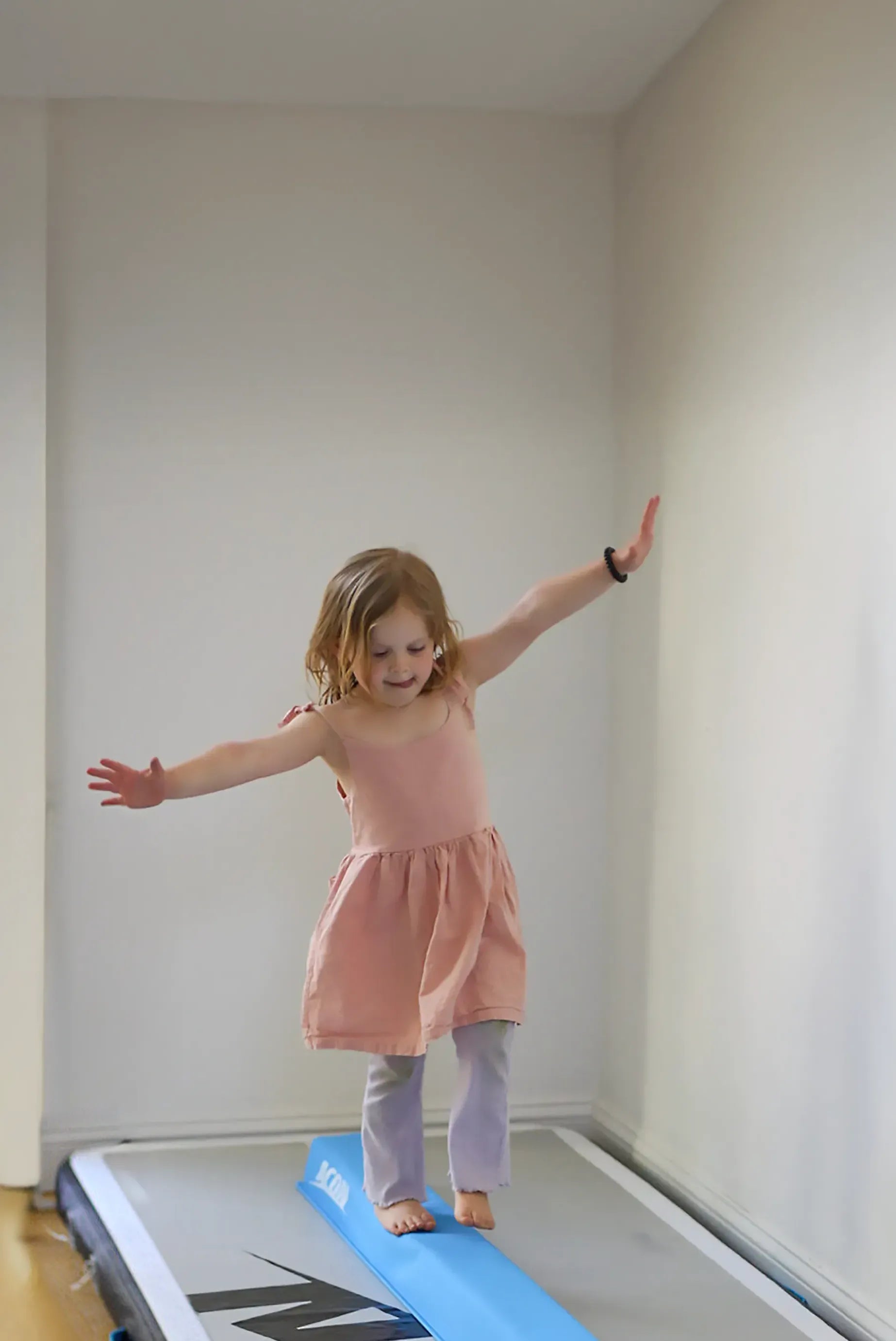 A little girl balances on an Acon Balance Beam and a 10-foot air track.