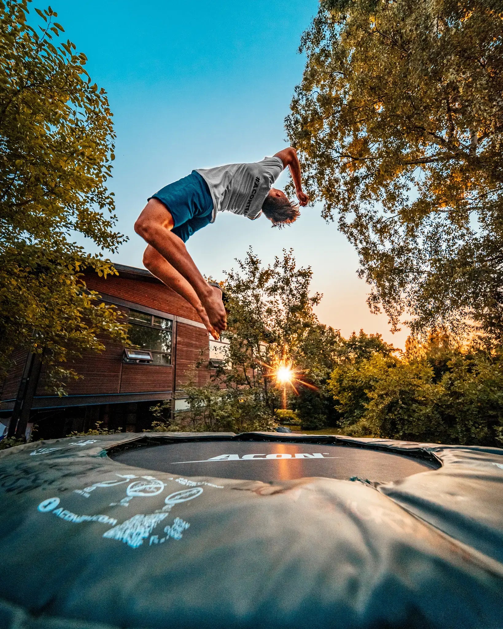 Professional athlete doing a backflip on a small round Acon trampoline. 