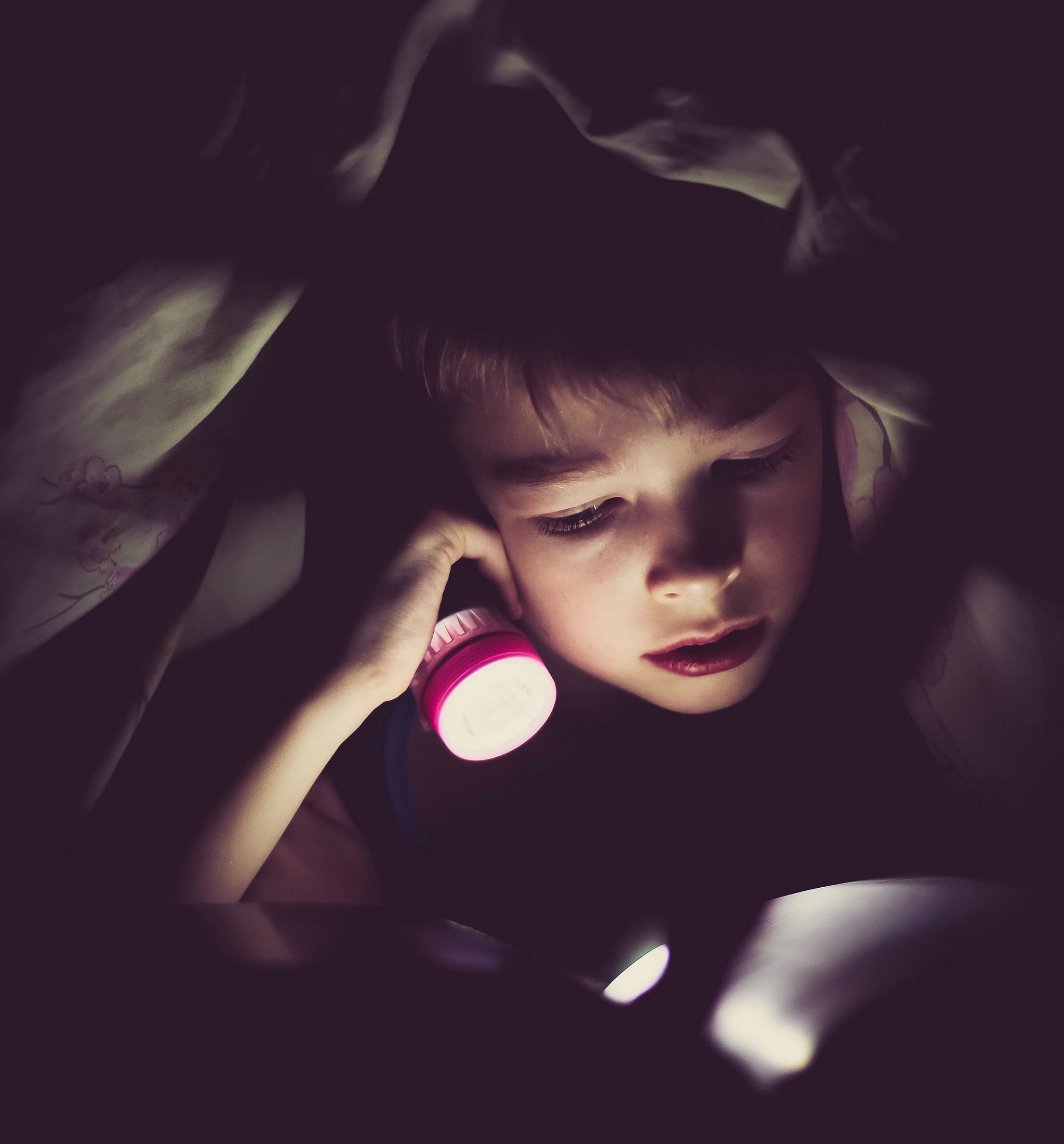 Kid reading in flashlight