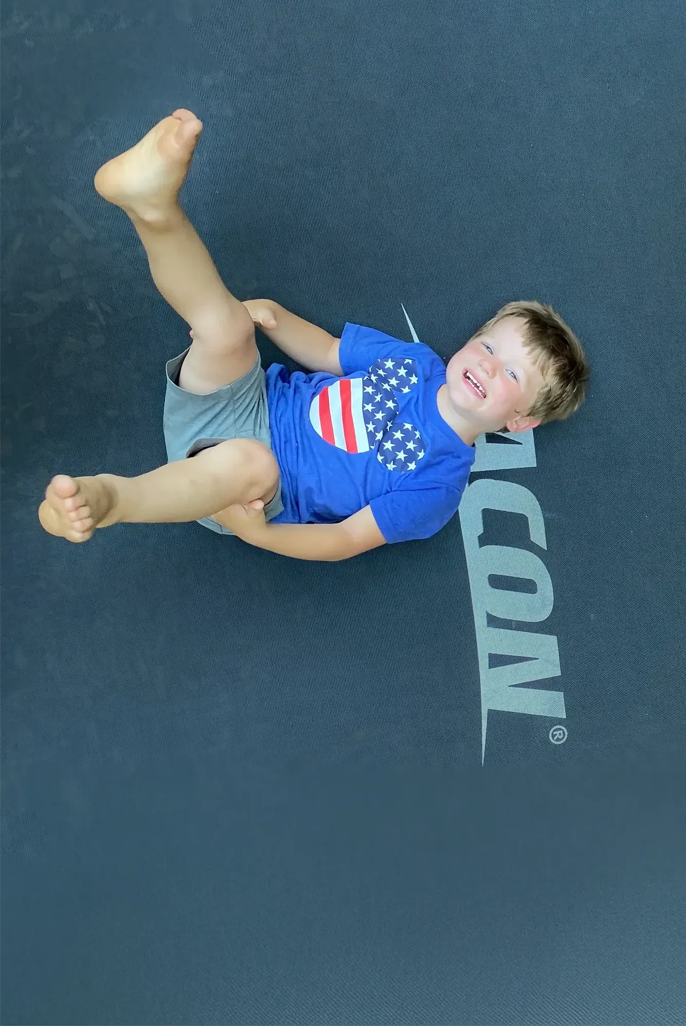 A happy boy wearing America-themed t-shirt on an Acon trampoline.