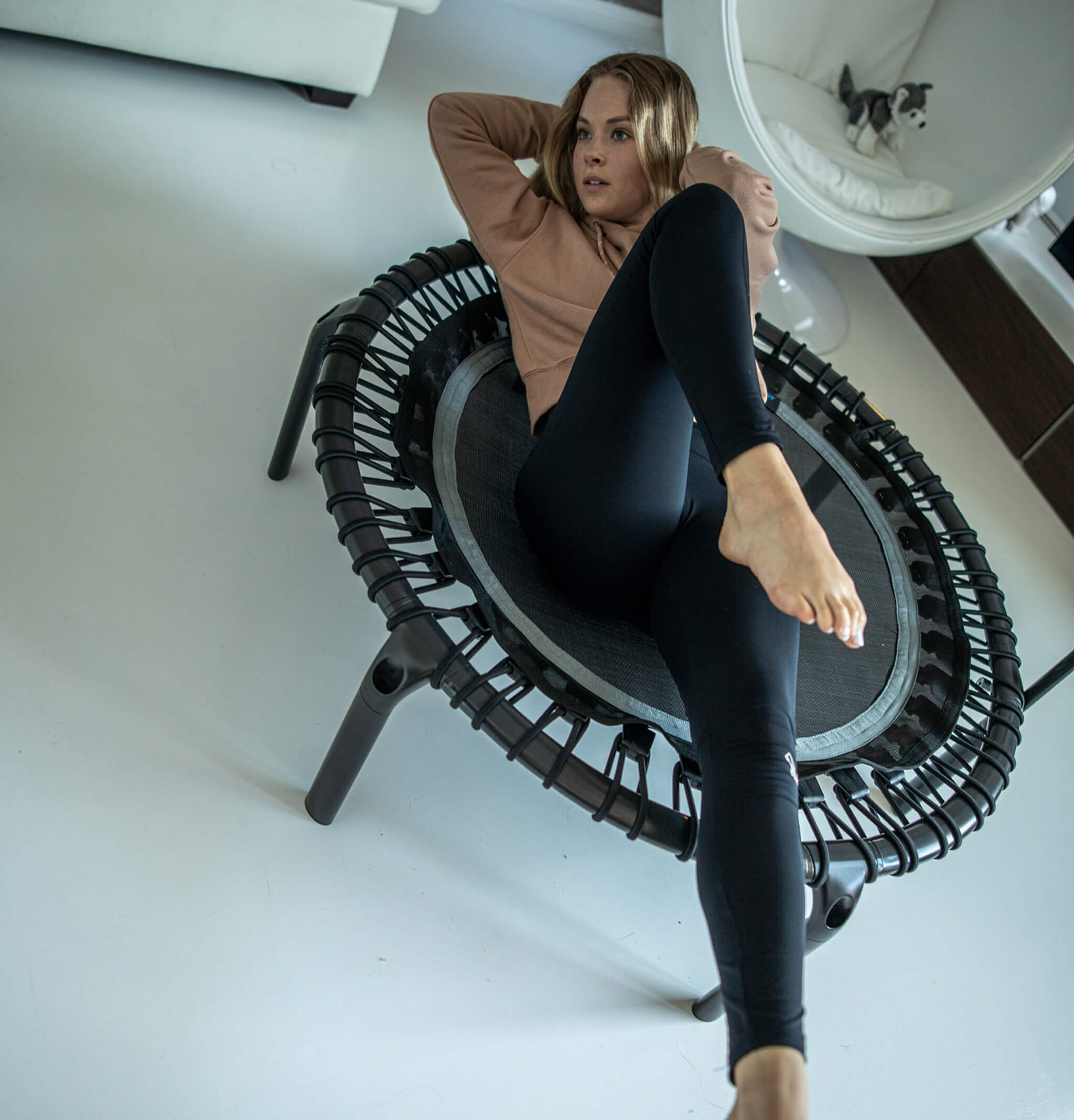 A woman is exercising on an Acon FIT rebounder in the living room.