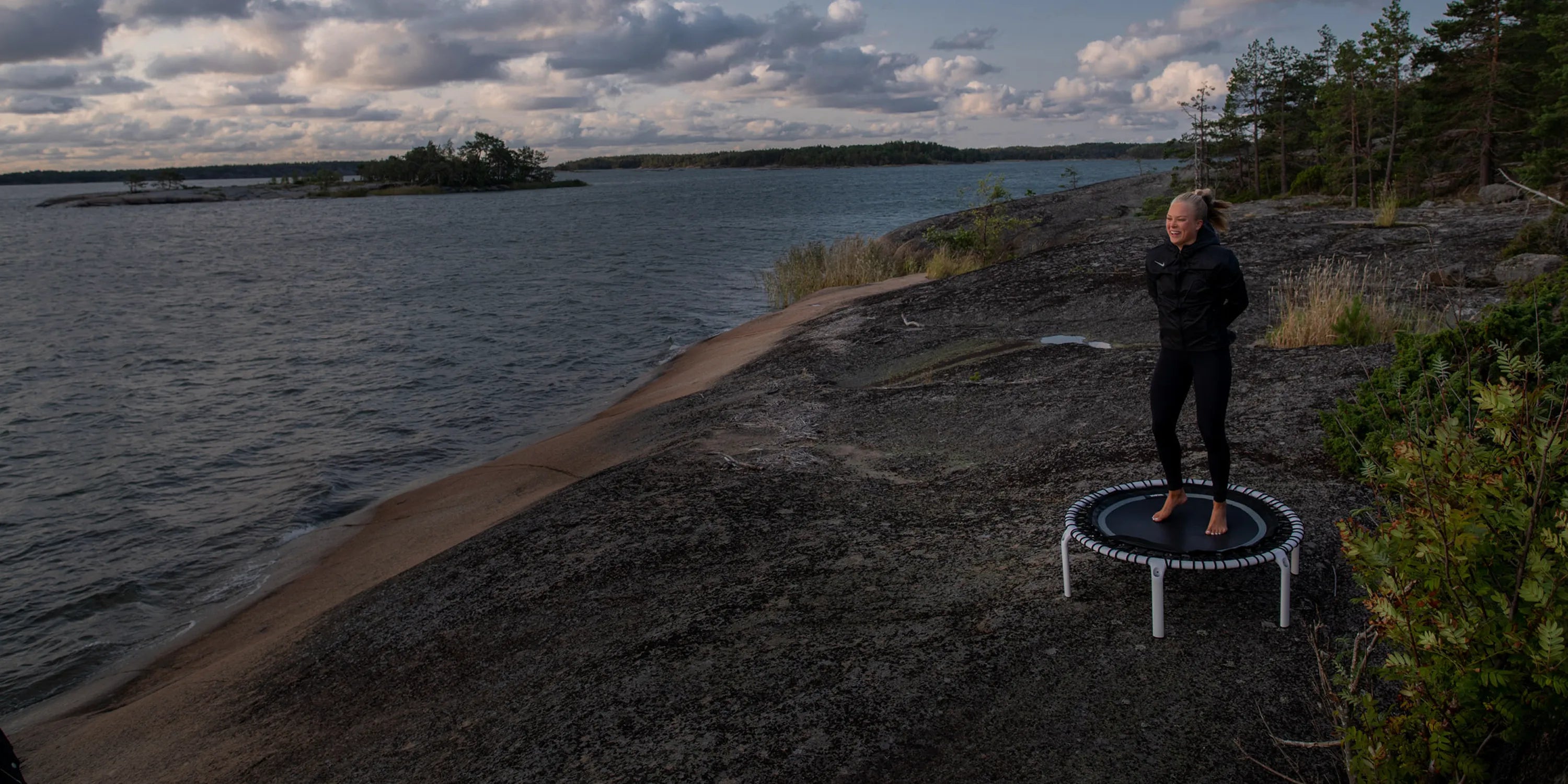 Fit 44in Round Rebounder with Balance Handlebar placed outdoors for balance training by the shoreline.
