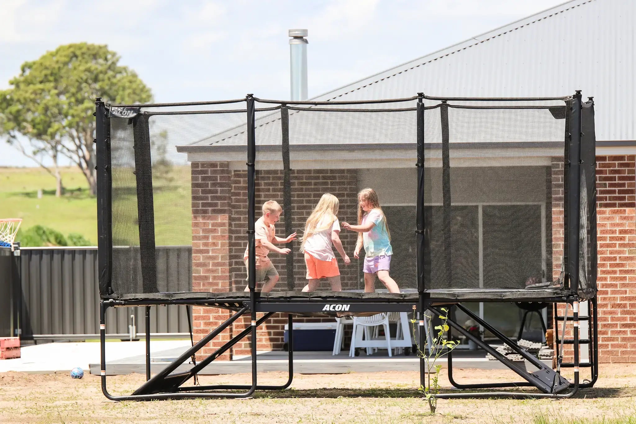 Three kids playing on a Acon X trampoline. 