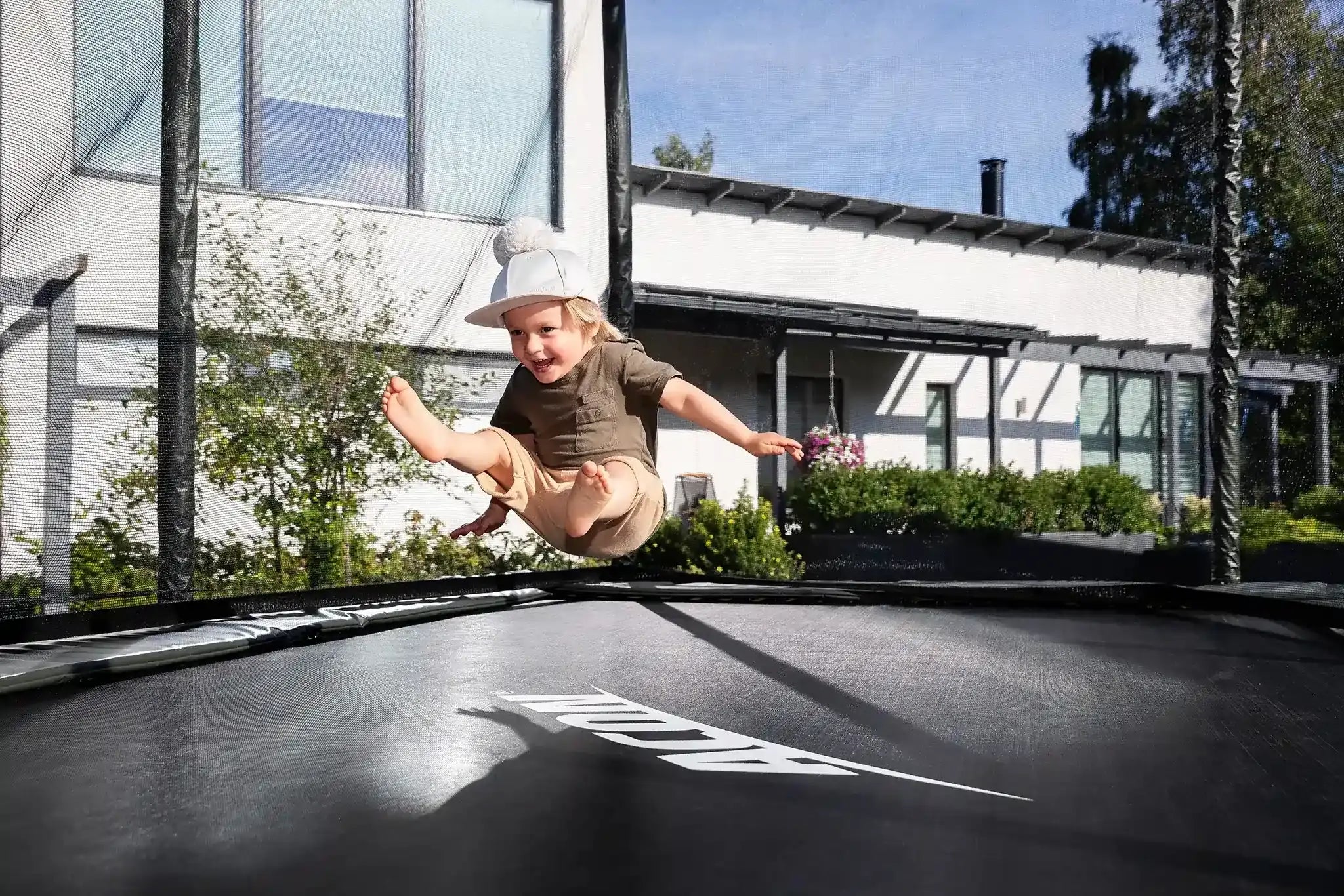 Toddler bouncing on a rectangular Acon trampoline with safety net. 