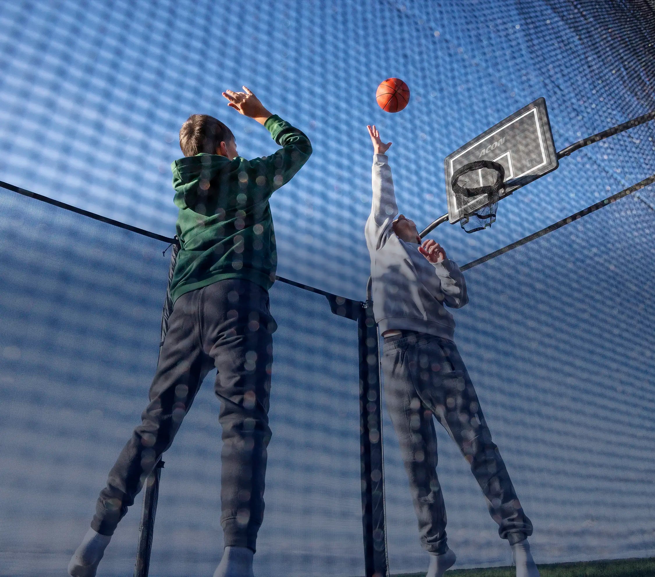 Two boys playing basketball on an Acon X Trampoline.