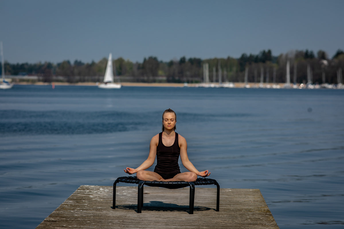 Woman sitting on a rebounder and practicing trampoline yoga