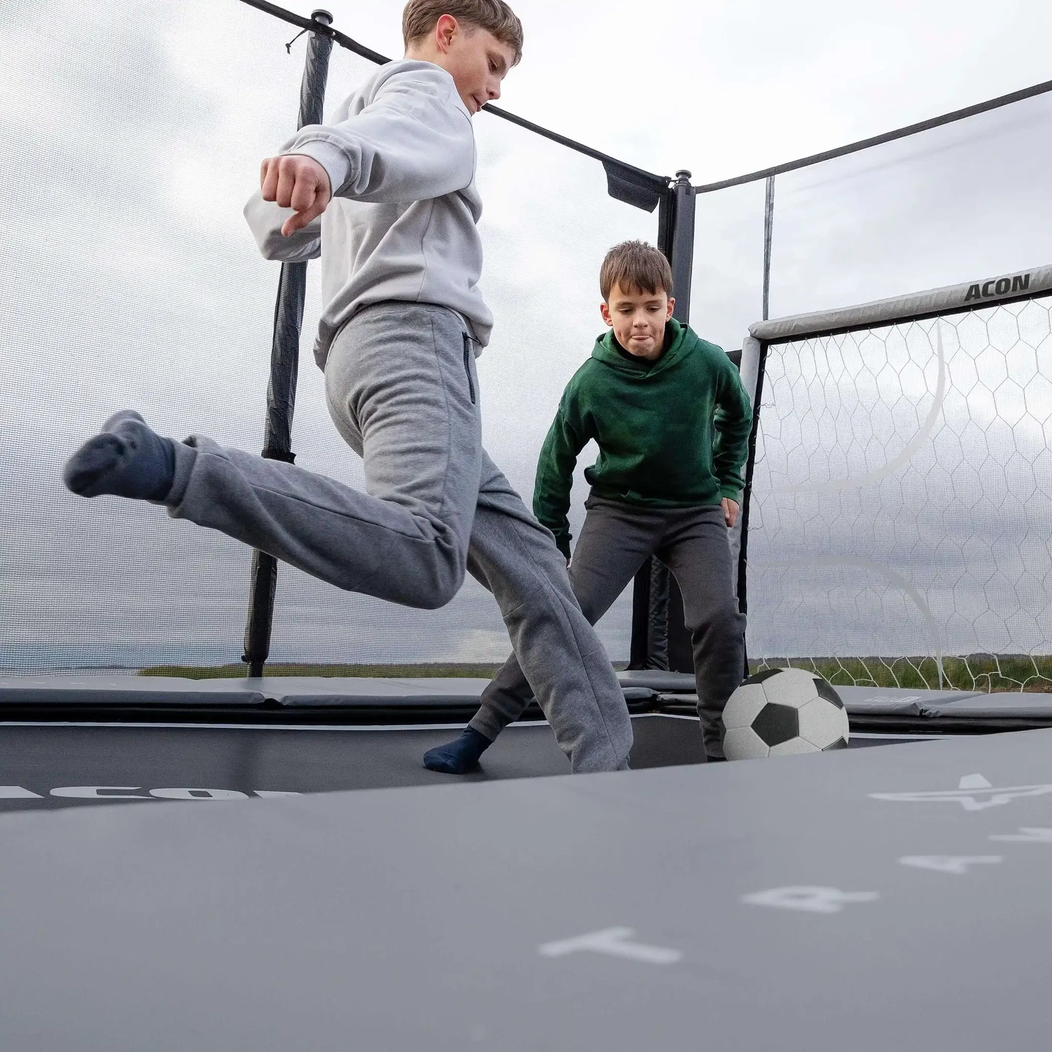 Two boys play trampoline soccer on the Acon X Trampoline.