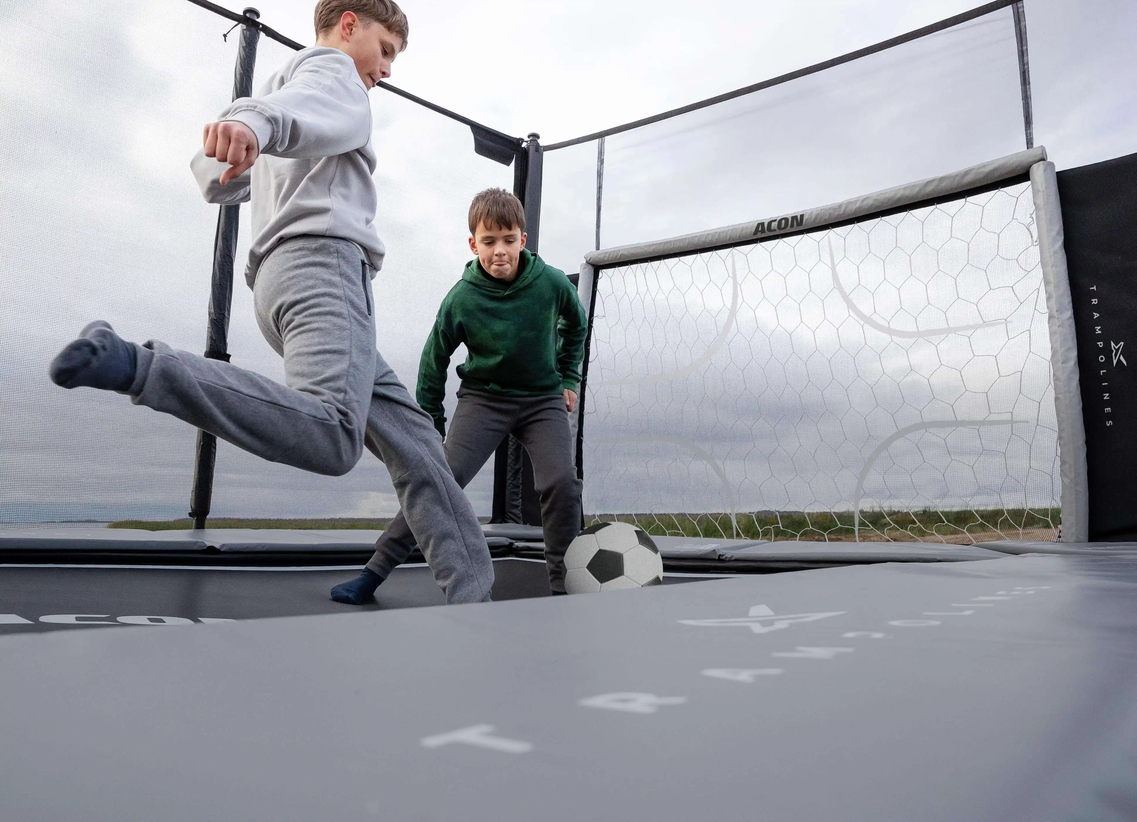 Two boys play trampoline soccer on the Acon X Trampoline.