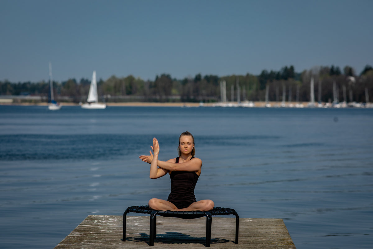 A woman sitting on an ACON round rebounder and stretching